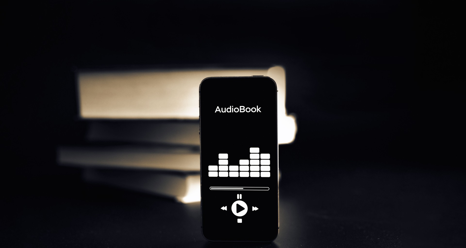 Audiobooks concept. Smartphone screen with audiobook application on paper books black background. Concept of education, library, students.